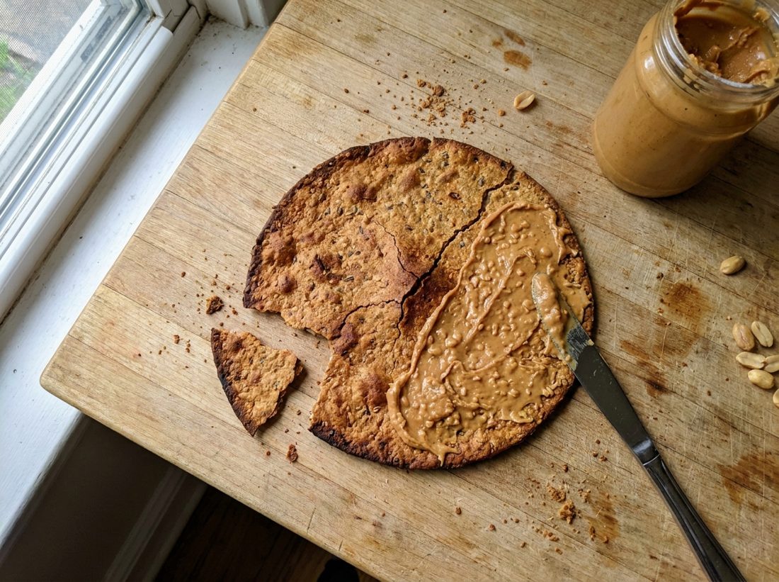 A crisp overcooked multigrain roti spread with chunky peanut butter